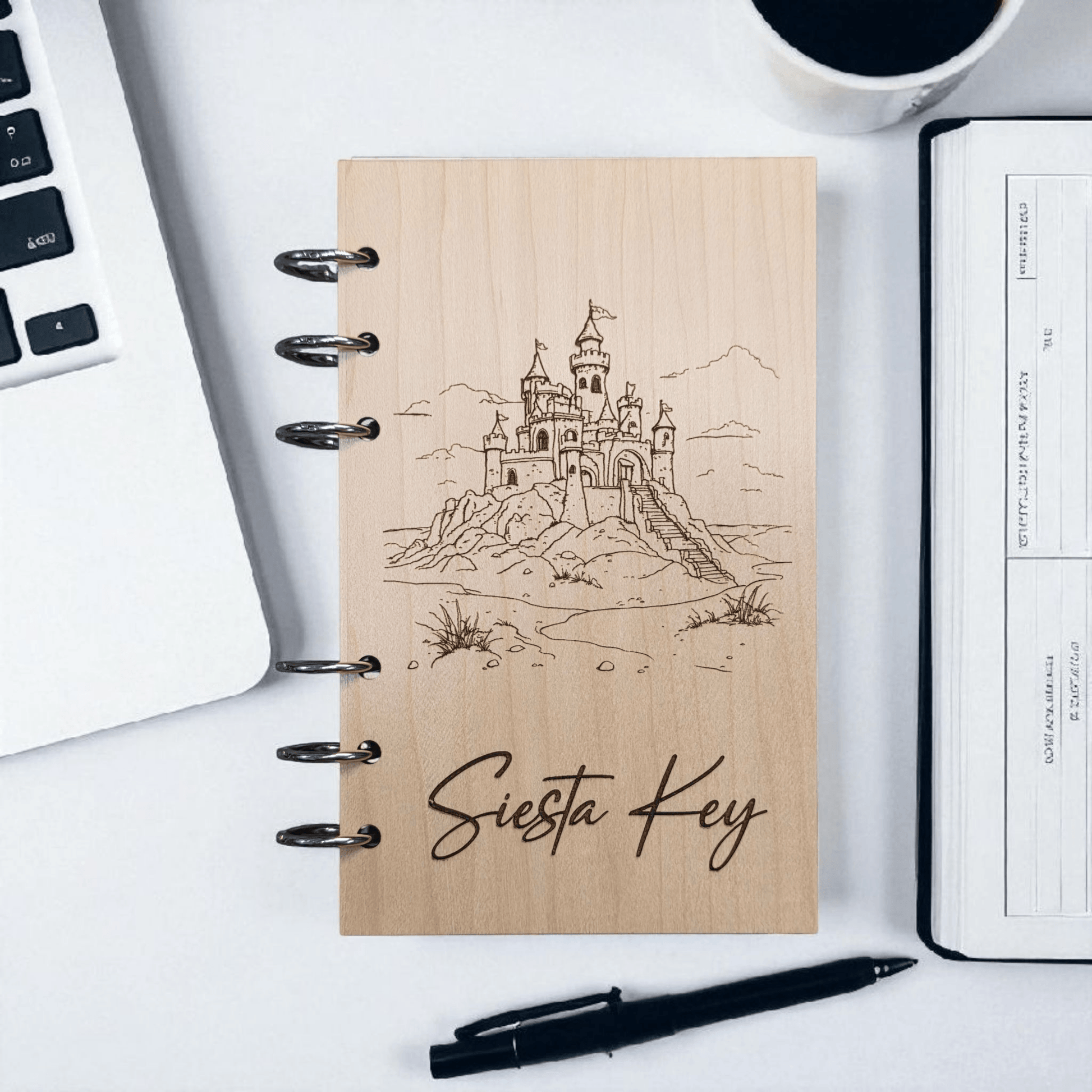 A6 refillable notebook with light tan cover, black spiral binding rings, line-art castle design