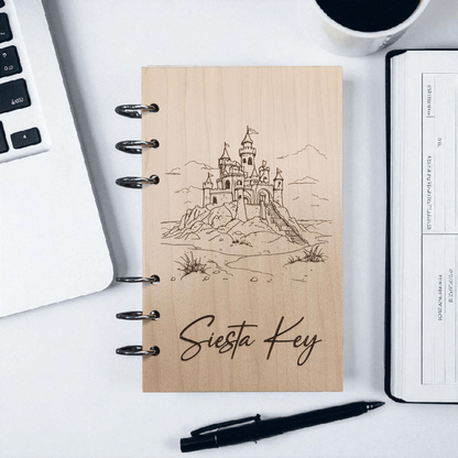 A6 refillable notebook with light tan cover, black spiral binding rings, line-art castle design