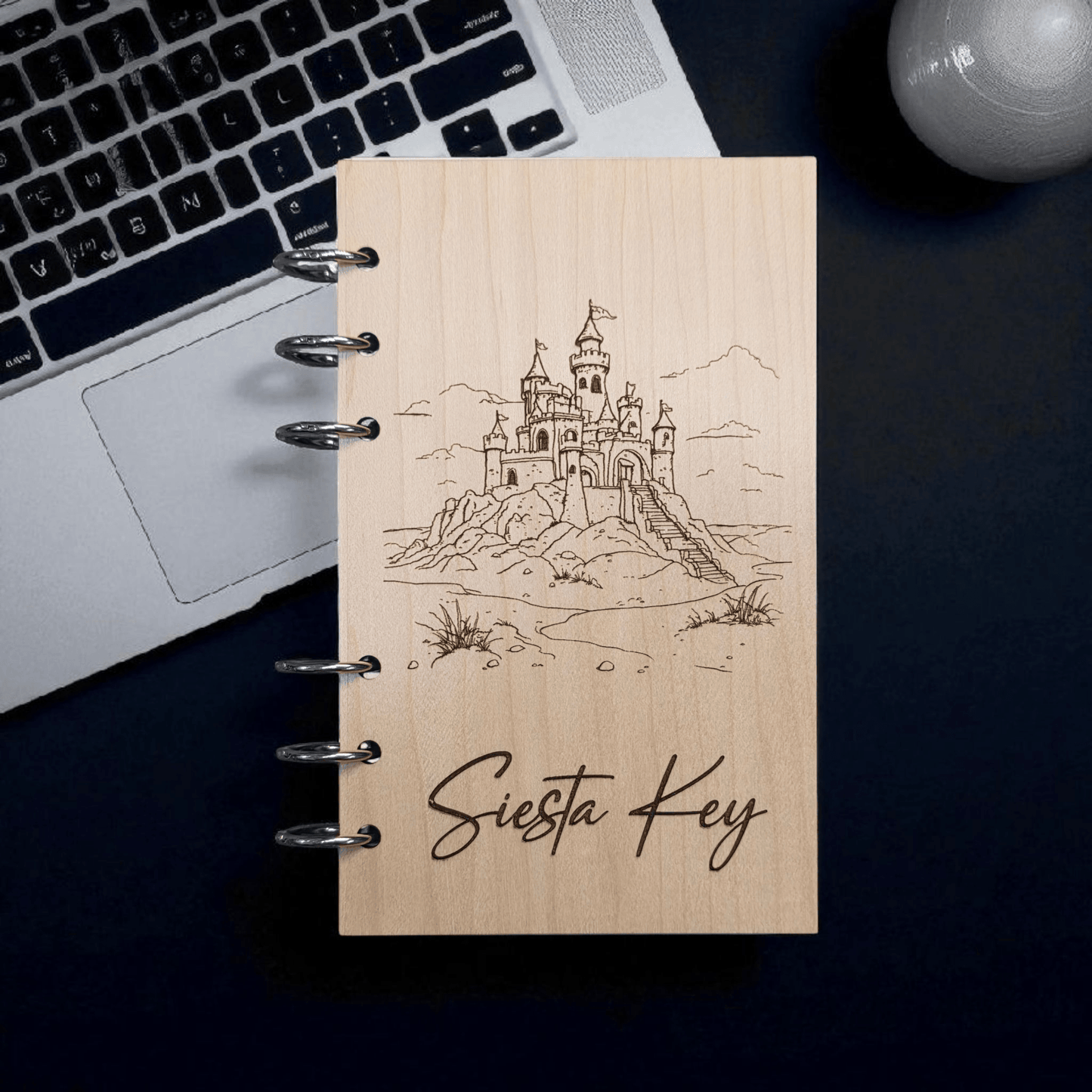 A6 refillable notebook front view with black spiral rings, line-art castle and Siesta Key