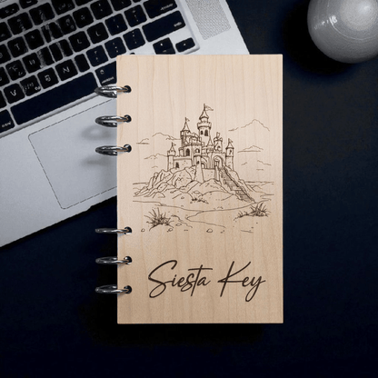 A6 refillable notebook front view with black spiral rings, line-art castle and Siesta Key