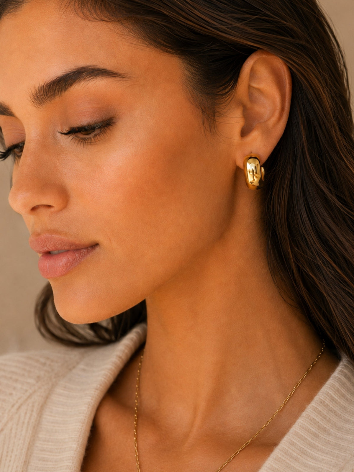 Close-up of gold dome hoop earrings with hinged post