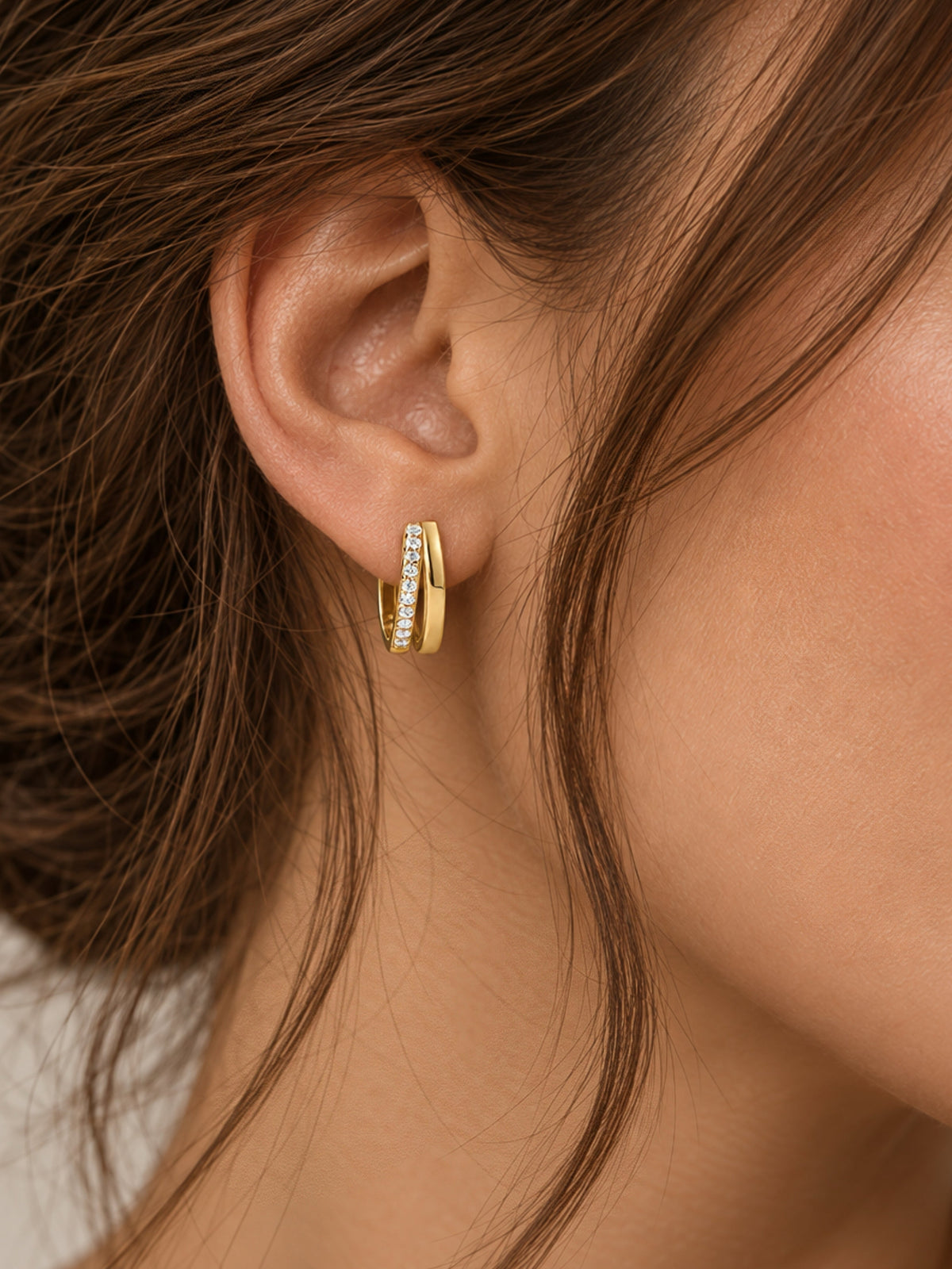 Gold hoop earrings with double pave row of clear stones, shown on ear