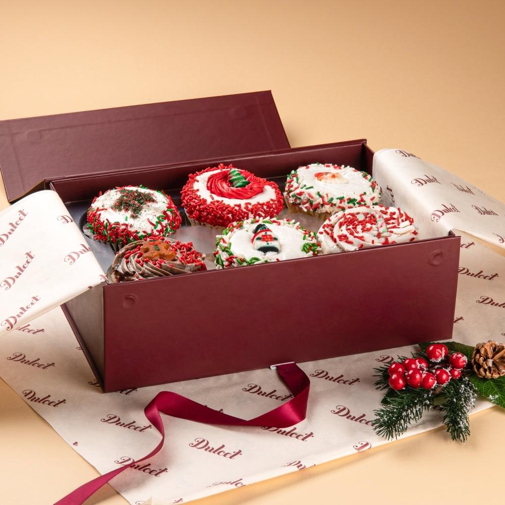 Assorted cupcakes in burgundy gift box, swirled frosting with holiday sprinkles