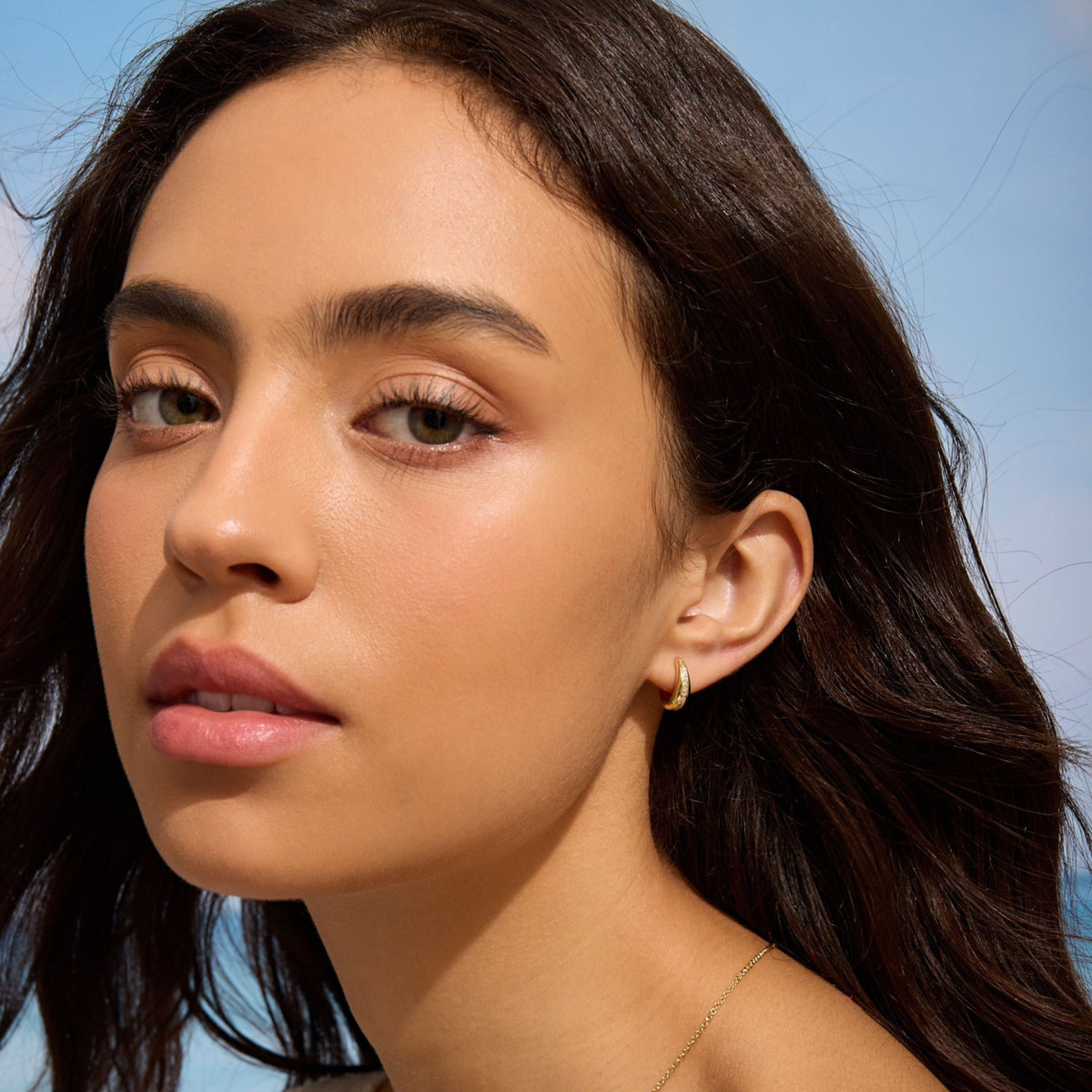 Gold teardrop huggie earrings worn by model, diamond row at front