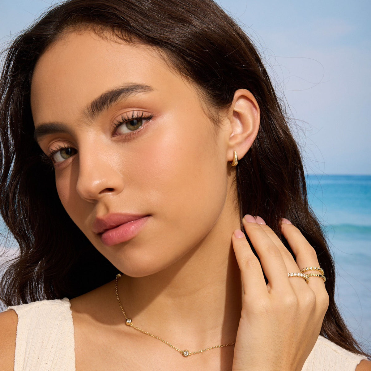 Gold teardrop diamond huggie earring on ear