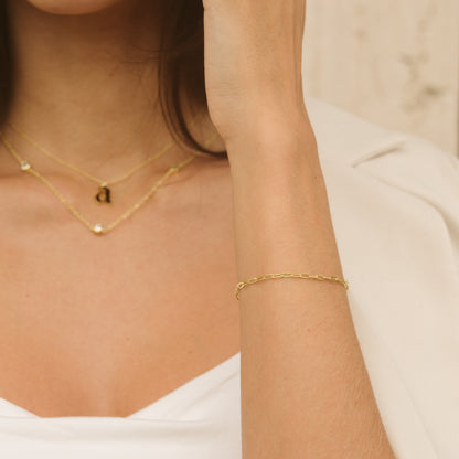 Gold paperclip chain bracelet around wrist, thin adjustable chain style
