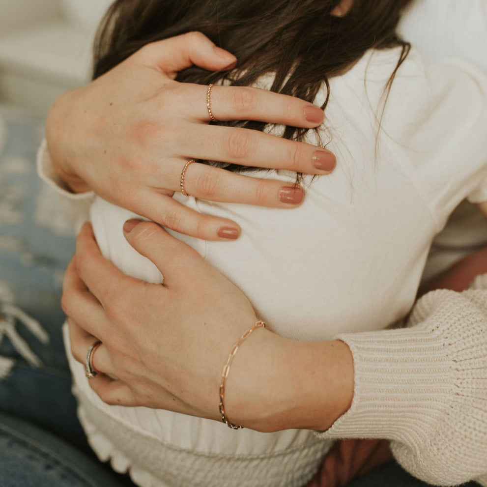 Gold-filled paperclip bracelet worn on the wrist beside delicate rings.