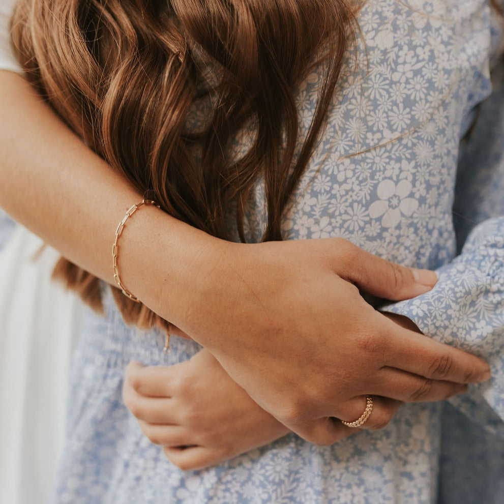 Gold-filled paperclip bracelet with elongated links, worn on the wrist.