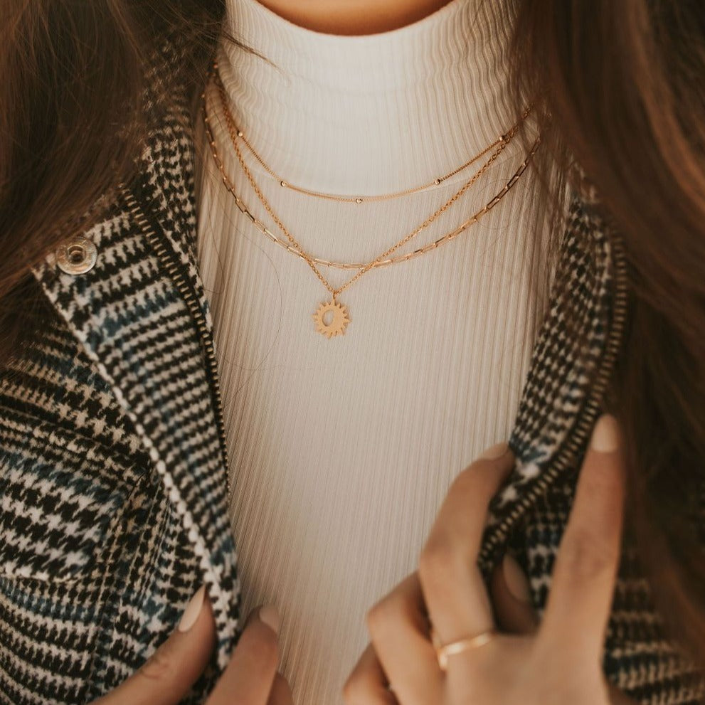Gold-filled paperclip necklace worn in a layered necklace stack.