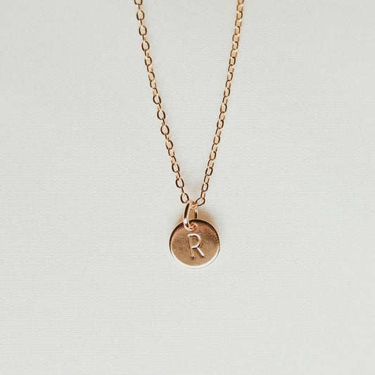 Gold-tone initial necklace with a round R charm on a fine chain