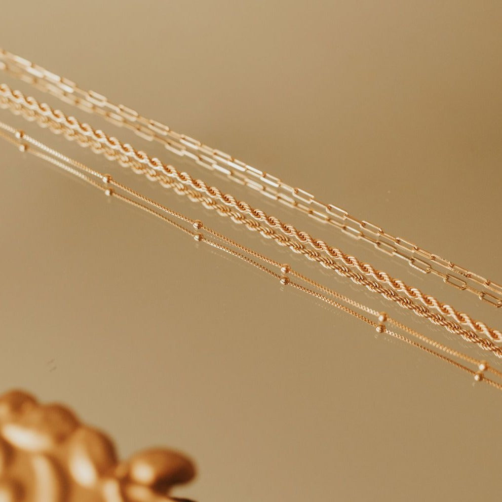 Gold-filled paperclip necklace shown alongside other delicate gold chains.