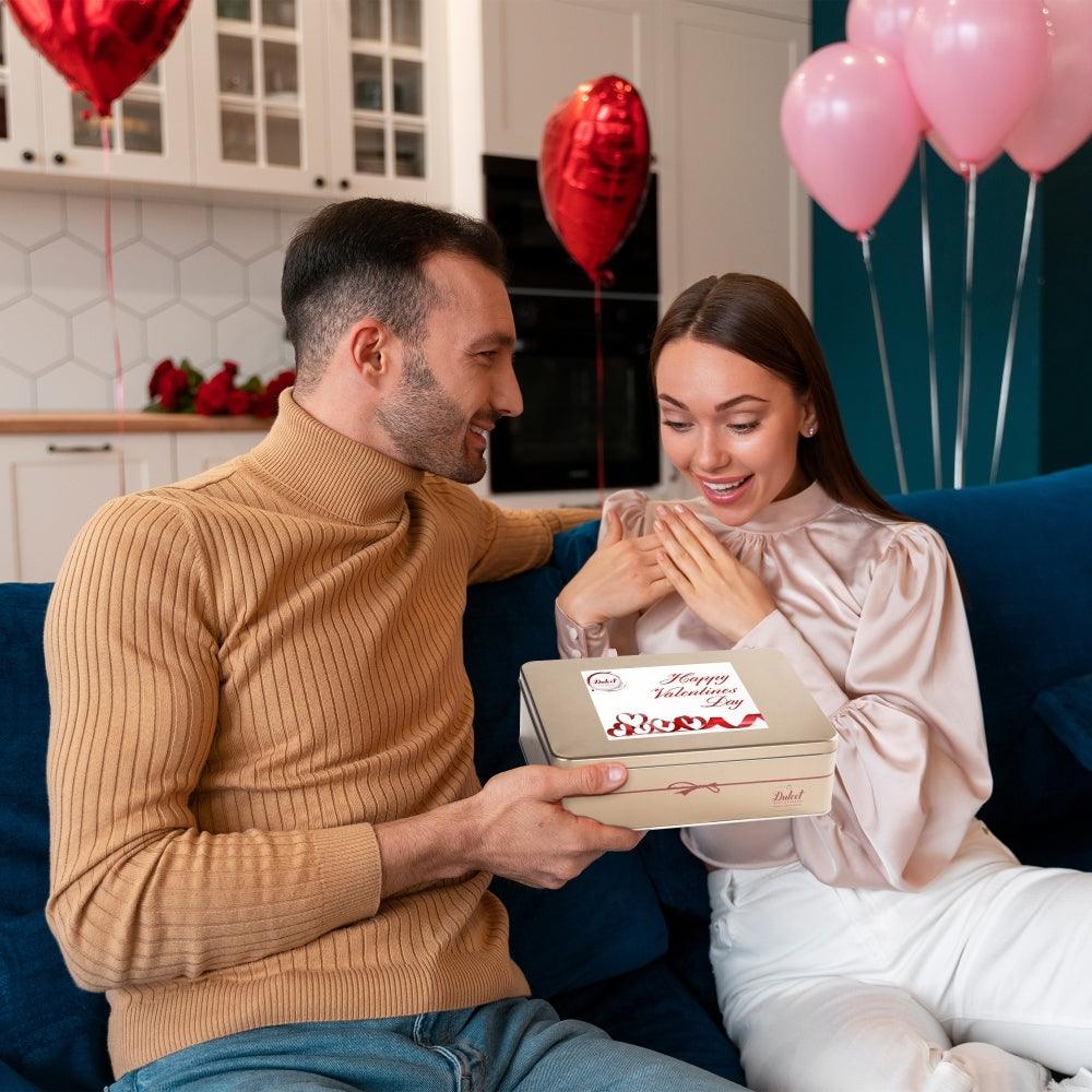 Paar überreicht eine Valentins-Geschenkbox, Person hält die Schachtel
