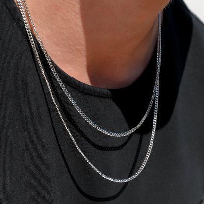 Two silver-tone Miami Cuban link chain necklaces with close neckline detail