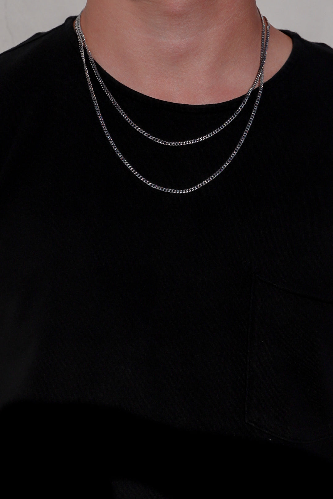 Single silver-tone Miami Cuban link chain necklace on a black shirt