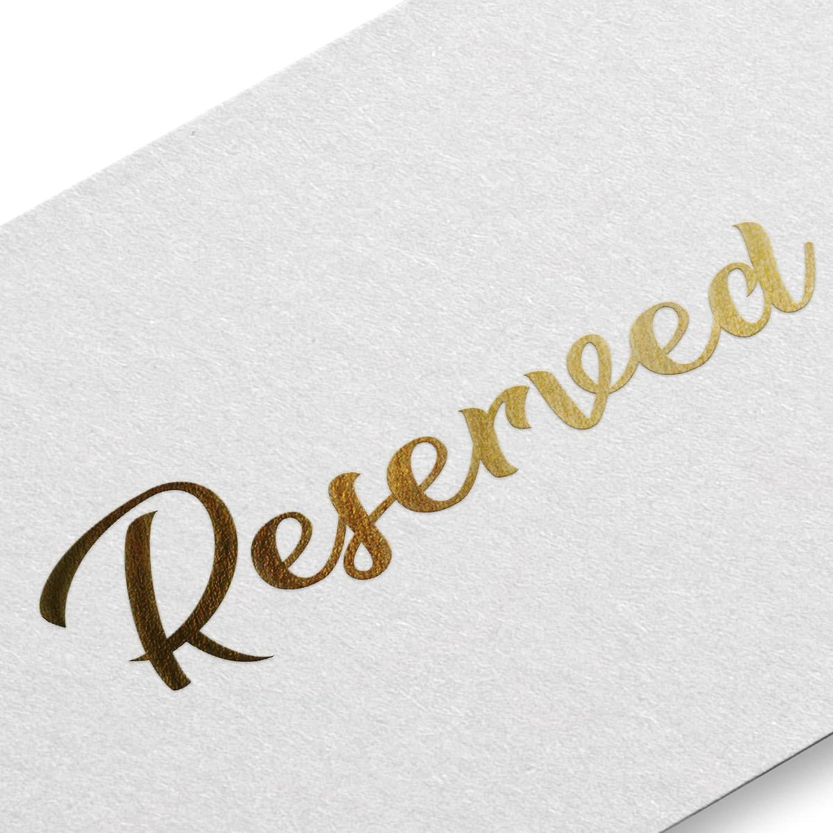 Close-up of white reserved table tent sign with gold “Reserved” script lettering