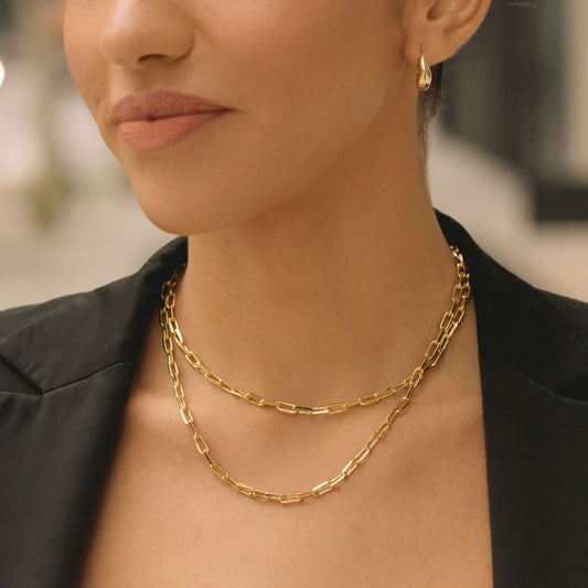 Layered gold-tone paperclip chain necklace on neckline