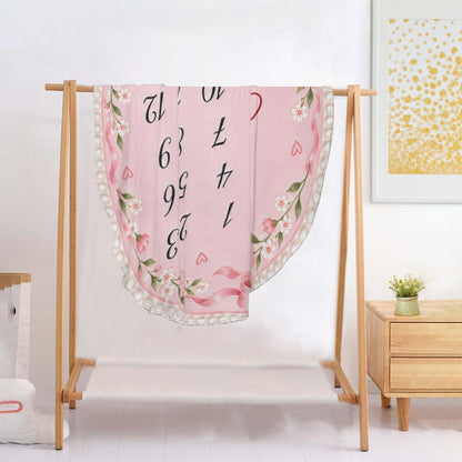 Pink round milestone blanket on stand with floral trim, numbers 1-12 and Charlotte