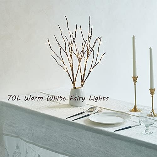 Warm white fairy light willow branches in white vase on table with candles