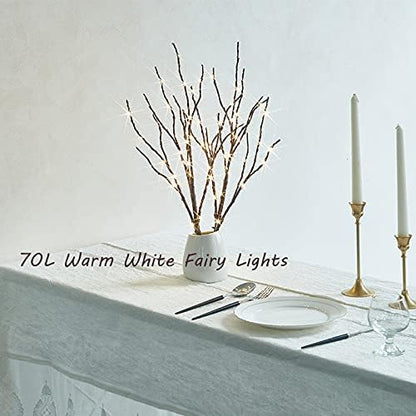 Warm white fairy light willow branches in white vase on table with candles