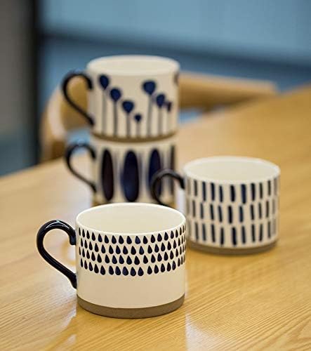 Group of patterned blue porcelain mugs with black handles on a tabletop