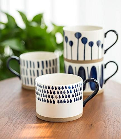 Four blue motif porcelain mugs with black handles on a wooden table