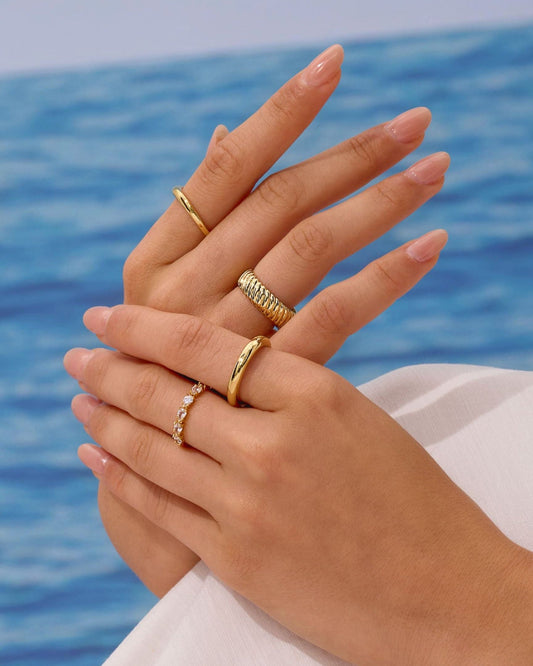 Gold-tone plain band ring on finger with smooth surface