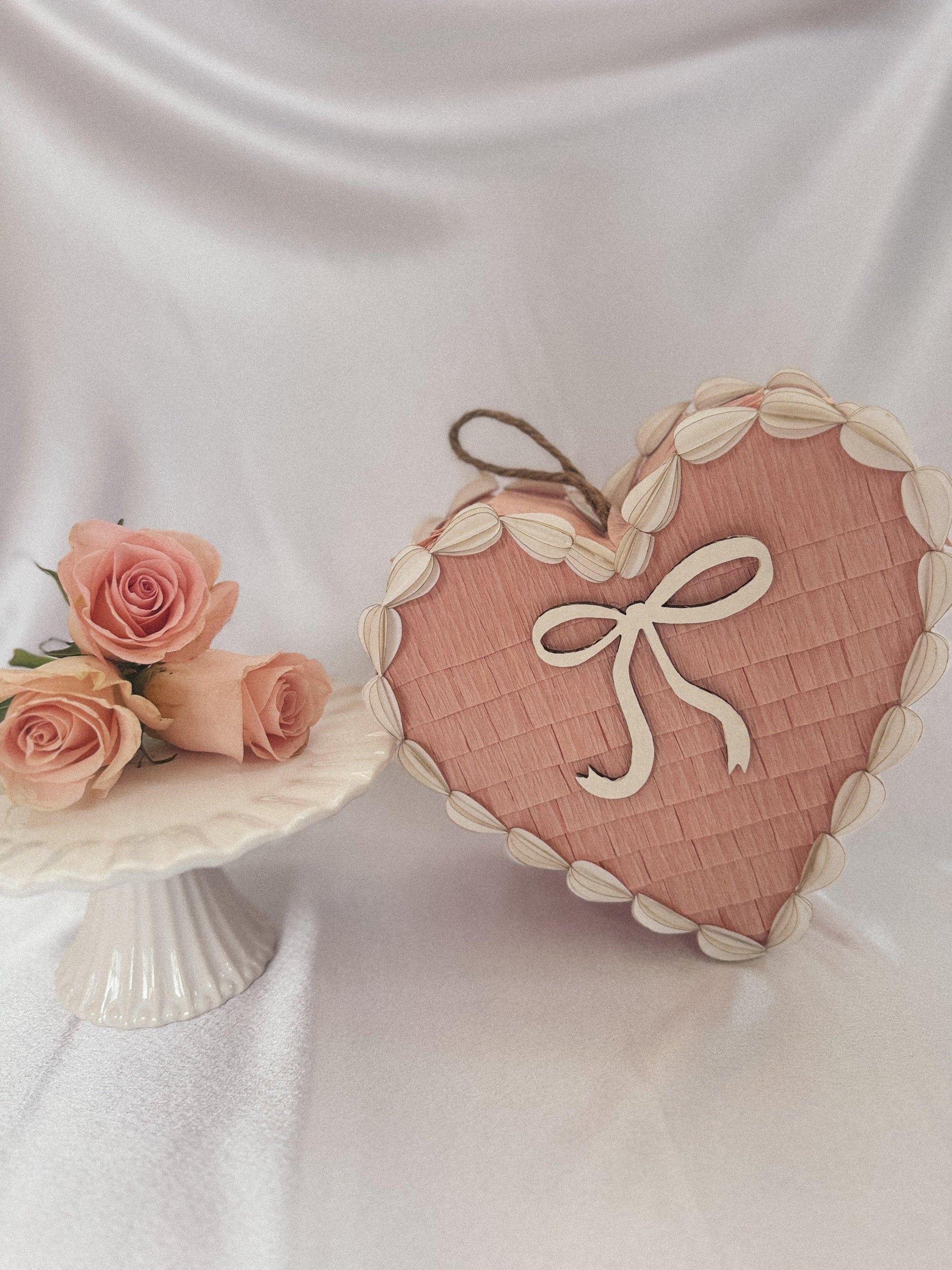 Corazón piñata de tarta San Valentín rosa con lazo blanco; contorno de hojas