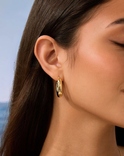 Gold chunky hoop earrings worn close-up on profile