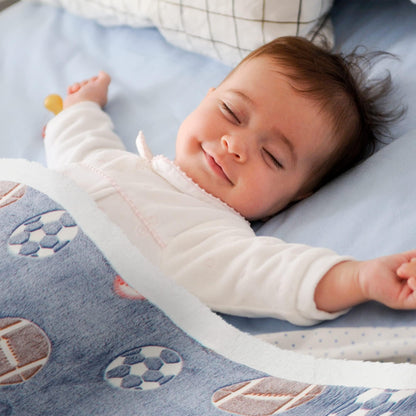 Gray sports blanket with soccer and football prints over a sleeping baby