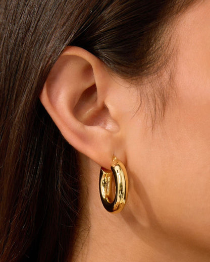 Gold chunky hoop earrings with glossy finish on ear
