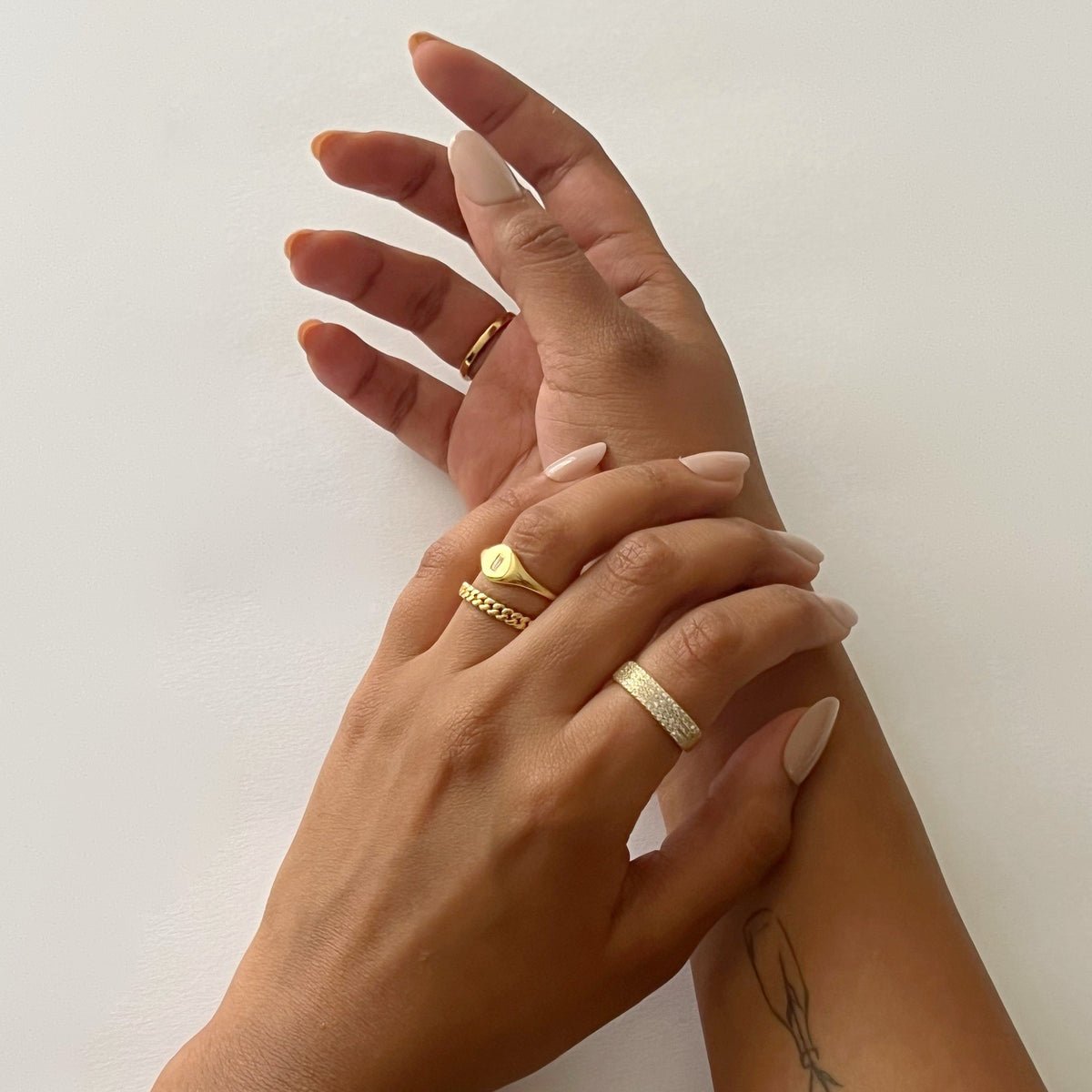 Stacked rings featuring a gold-tone pavé band ring with sparkling stones