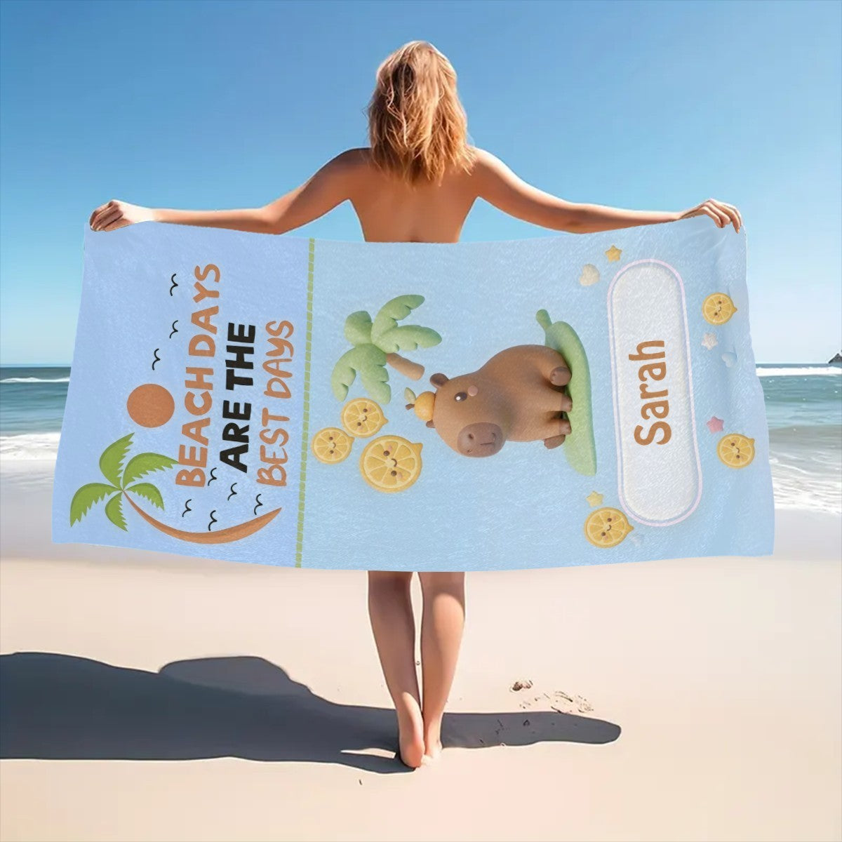 Light blue beach towel across arms with bear, lemons, palms, and Saran label on edge.