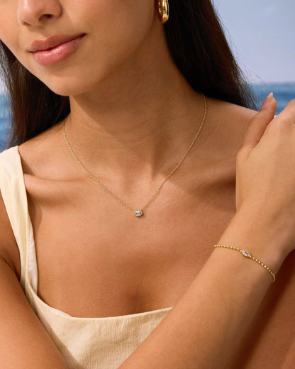 Gold oval diamond pendant necklace with matching beaded bracelet on model