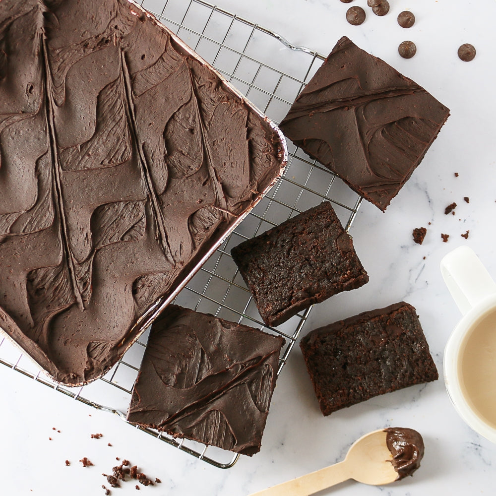 Dark chocolate cookie bars cooling on a rack, partly inside a metal tin tray