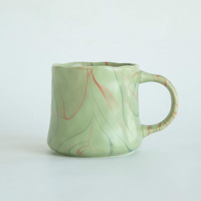 Mint green ceramic coffee mug with abstract red and white accents, curved handle