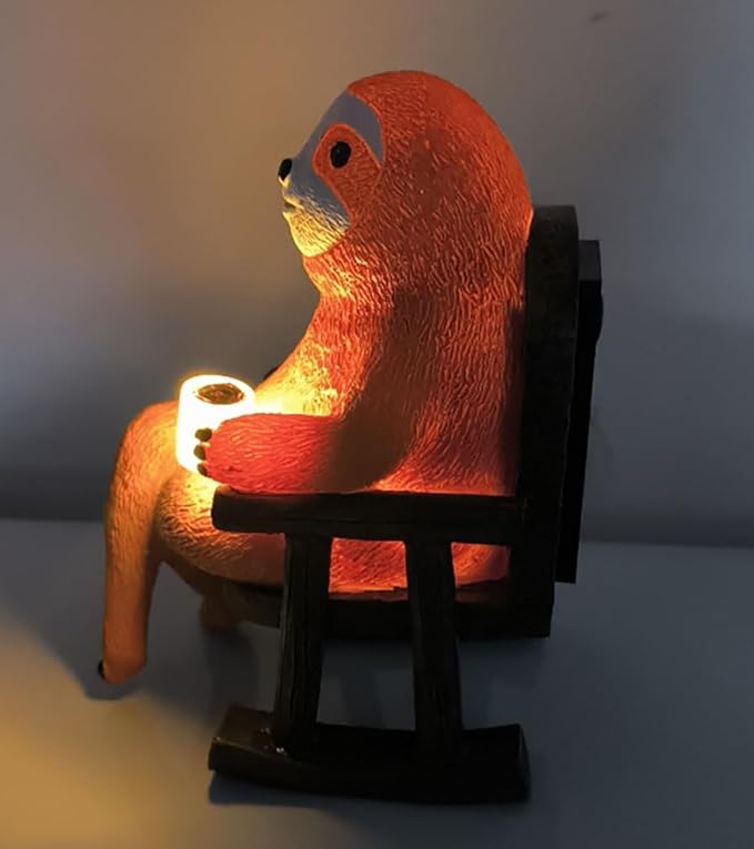 Solar light sloth figurine holding a cup on dark chair, warm light glowing.