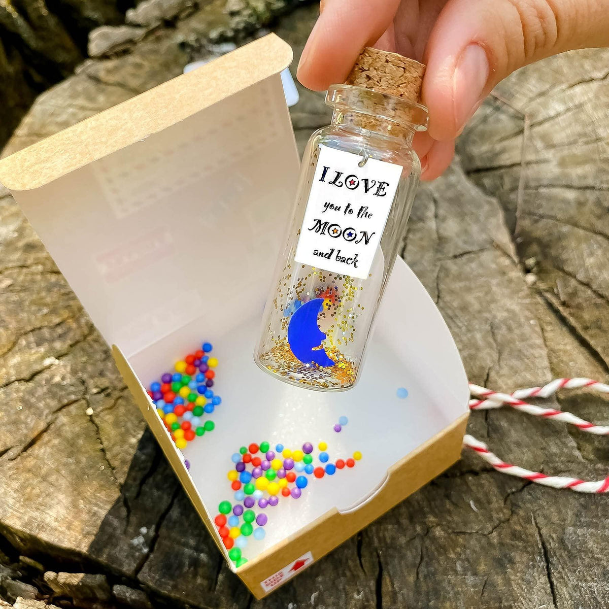 Corked moon-themed bottle with glitter contents, shown with open craft gift box