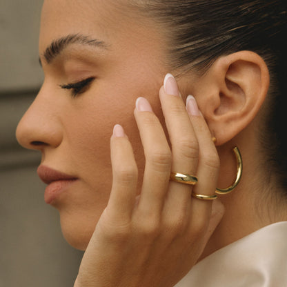 Gold wavy dome ring on hand, polished raised dome with wavy profile
