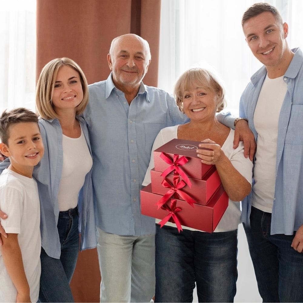 Family holding a burgundy gift box tied with a pink ribbon bow