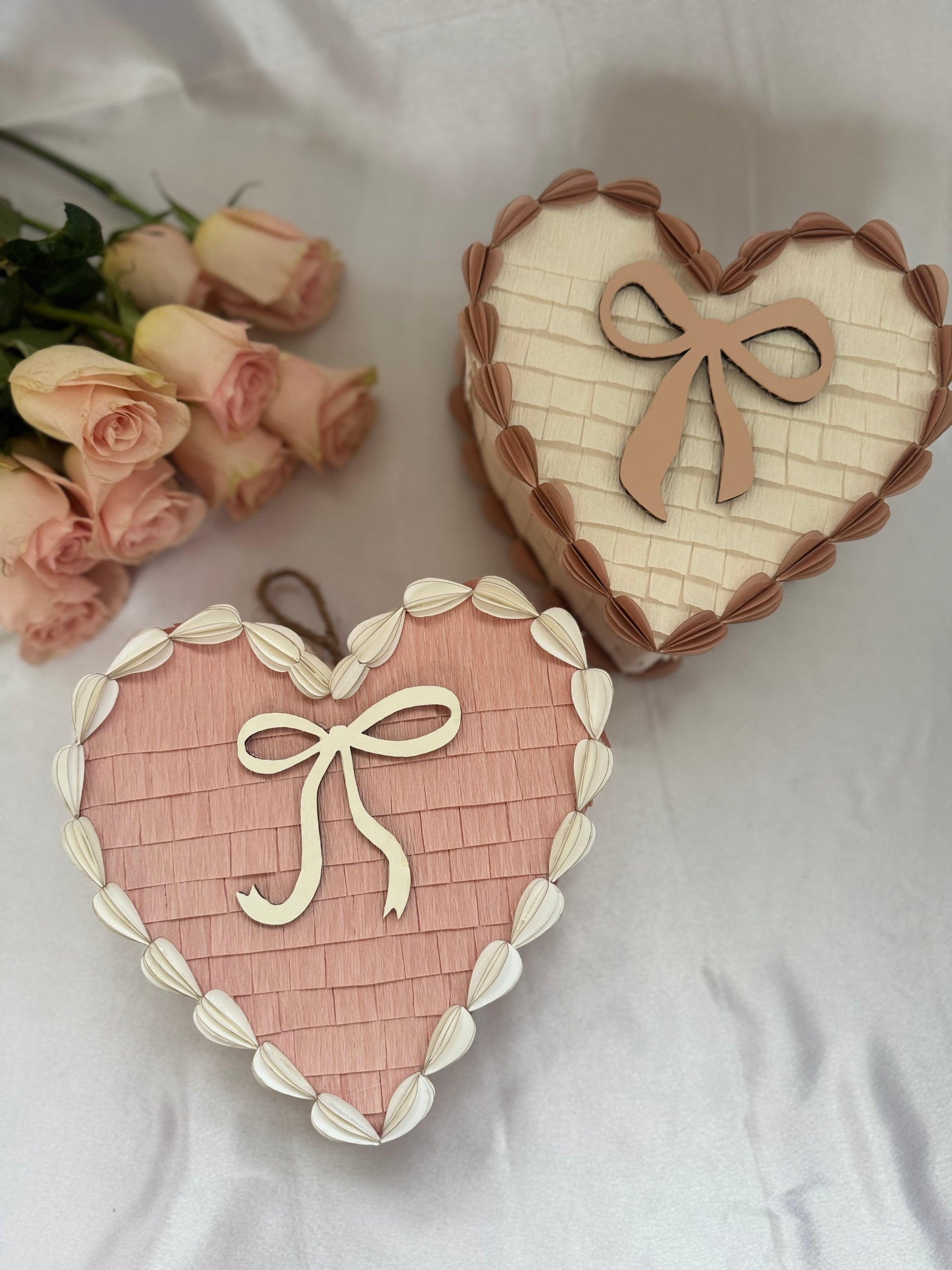 Dos corazones piñata de tarta San Valentín: rosa y crema, con lazos blancos