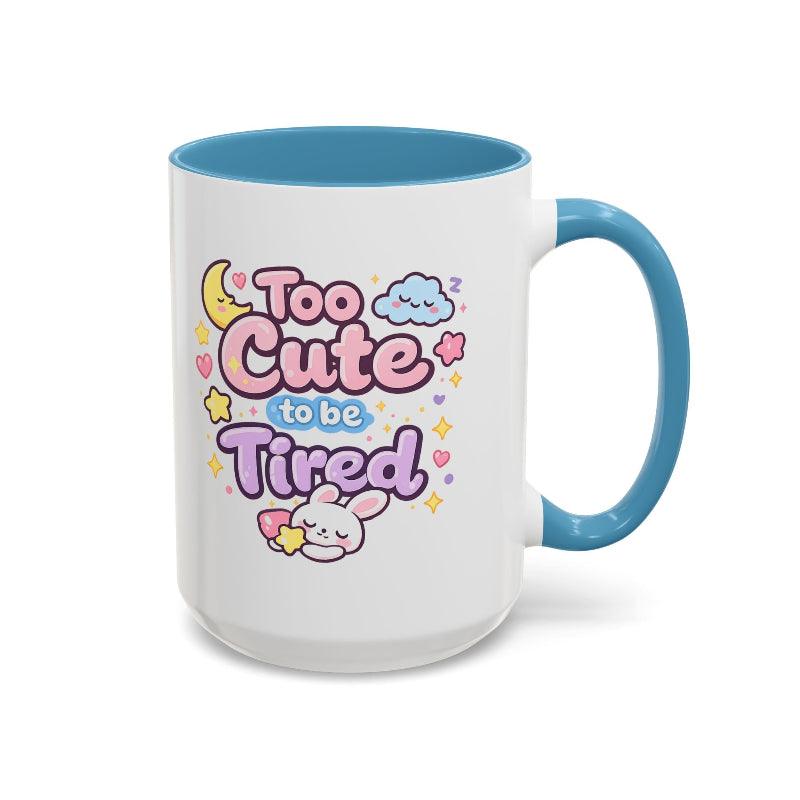 White mug with blue rim and handle, “Too Cute to be Tired” text with bunny.