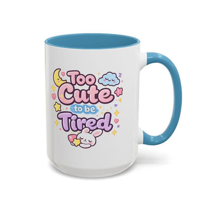 White mug with blue rim and handle, “Too Cute to be Tired” text with bunny.