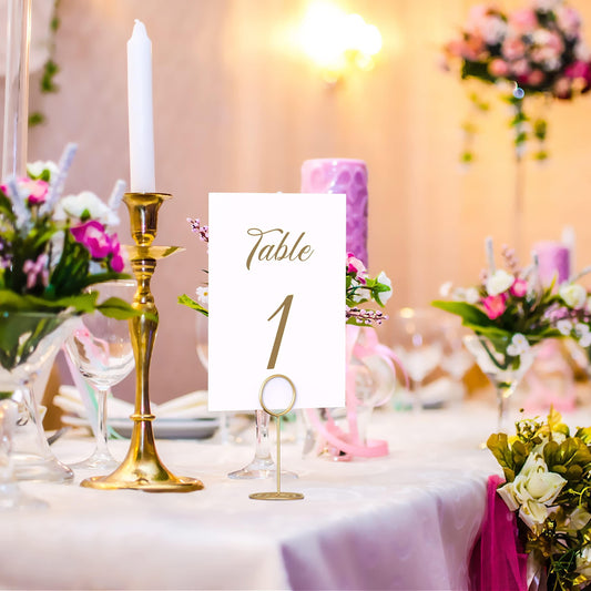 Gold card clip table number holder standing in front of a floral wedding table