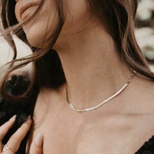 Gold herringbone necklace worn close around the neck