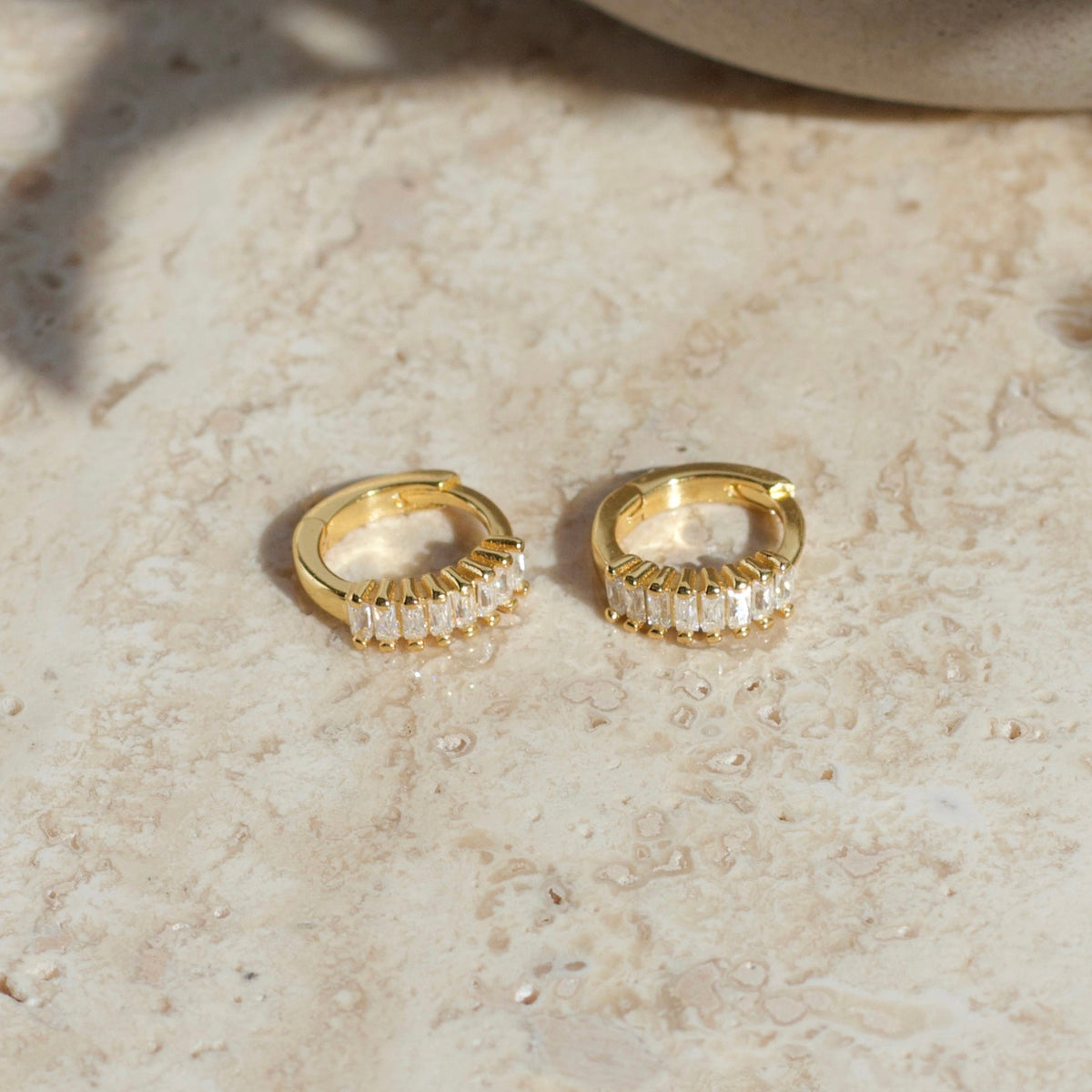 Pair of gold huggie hoop earrings with baguette-cut crystal detailing
