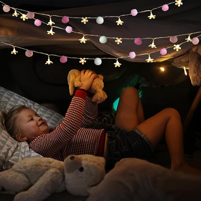 Cherry blossom string lights with pink and white pom poms and warm flower LEDs above bed