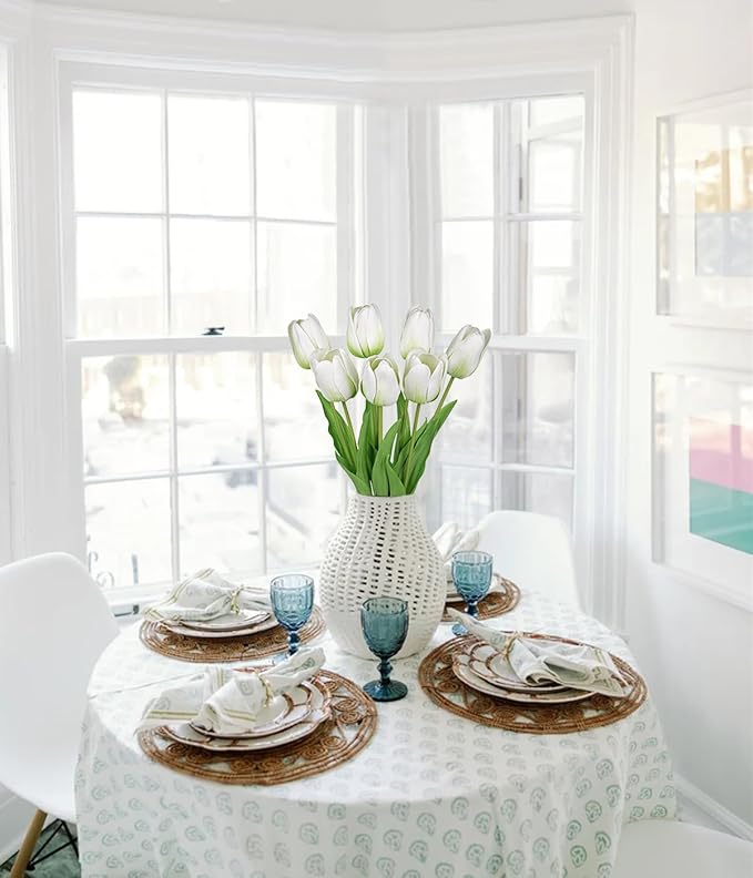 Artificial white tulip stems in a textured vase on a dining table centerpiece