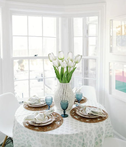 Artificial white tulip stems in a textured vase on a dining table centerpiece