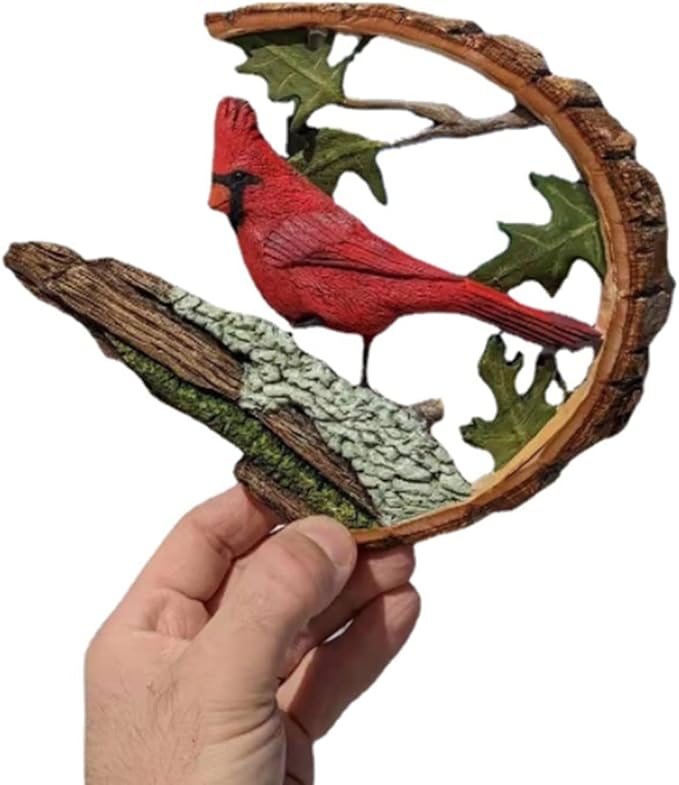 Wooden cardinal bird sculpture in hand, red cardinal perched on branch under leaf arch