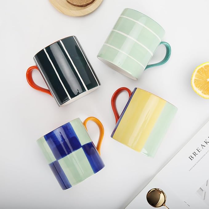 Set of four glazed ceramic mugs in black, mint, blue, and yellow with matching colorful handles